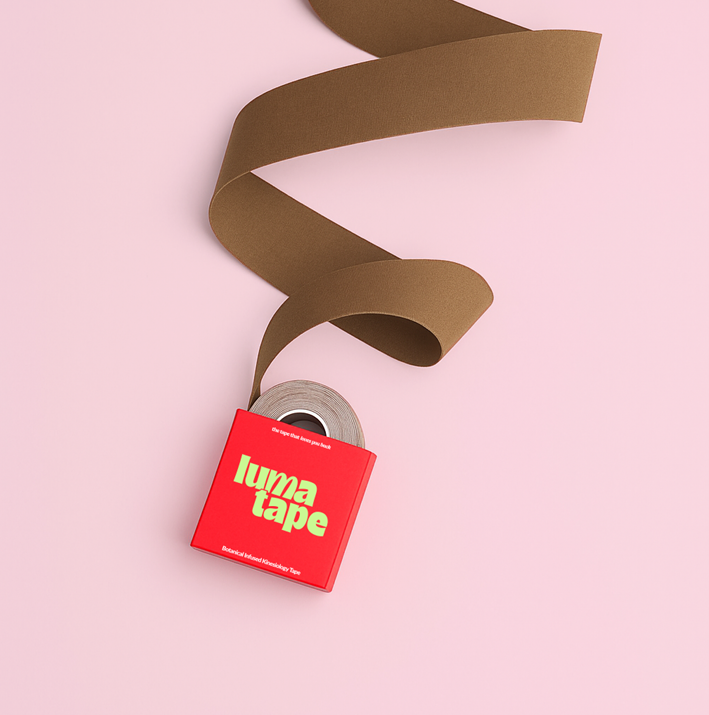 Pregnant woman using LumaTape on lower back for gentle support